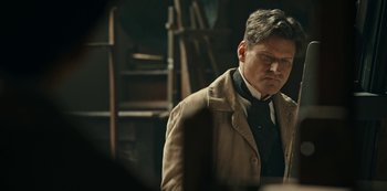 Movie still from “Guillermo del Toro's Cabinet of Curiosities” (2022), directed by Keith Thomas – A man wearing a suit and tie standing in a room; Medium shot, Over the shoulder angle