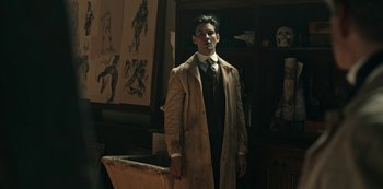 Movie still from “Guillermo del Toro's Cabinet of Curiosities” (2022), directed by Keith Thomas – A man standing in front of a painting in a room; Medium shot, Low angle