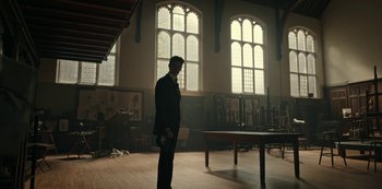 Movie still from “Guillermo del Toro's Cabinet of Curiosities” (2022), directed by Keith Thomas – A man standing in a room with a table in front of him; Wide shot, Low angle
