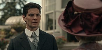 Movie still from “Guillermo del Toro's Cabinet of Curiosities” (2022), directed by Keith Thomas – A man wearing a suit and tie standing in front of a building; Close Up shot, Over the shoulder angle