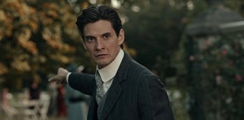 Movie still from “Guillermo del Toro's Cabinet of Curiosities” (2022), directed by Keith Thomas – A man wearing a suit and tie in front of trees; Close Up shot, Low angle