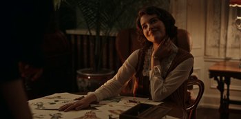 Movie still from “Guillermo del Toro's Cabinet of Curiosities” (2022), directed by Keith Thomas – A woman sitting at a table with her hand under her chin; Medium shot, Over the shoulder angle