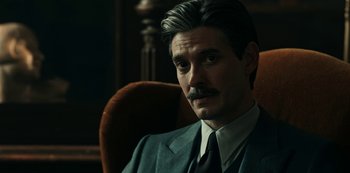Movie still from “Guillermo del Toro's Cabinet of Curiosities” (2022), directed by Keith Thomas – A person sitting in a chair wearing a suit; Close Up shot, Over the shoulder angle