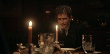 Movie still from “Guillermo del Toro's Cabinet of Curiosities” (2022), directed by Keith Thomas – A man sitting at a dinner table with a glass of red wine; Medium shot, Over the shoulder angle