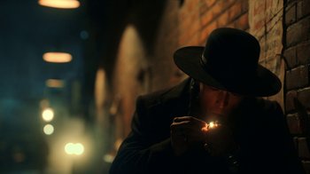 Movie still from “Guillermo del Toro's Cabinet of Curiosities” (2022), directed by Keith Thomas – A man wearing a hat and holding a lit cigarette; Close Up shot, Low angle