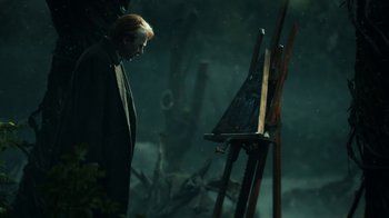 Movie still from “Guillermo del Toro's Cabinet of Curiosities” (2022), directed by Keith Thomas – A man standing in front of an easel in the dark; Medium shot, Over the shoulder angle