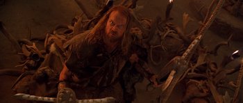 Movie still from “The Scorpion King” (2002), directed by Chuck Russell – A man with long hair and a goatee is holding a sword; Medium shot, Low angle