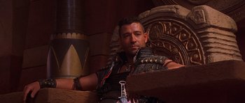 Movie still from “The Scorpion King” (2002), directed by Chuck Russell – A man in a leather vest sitting in a chair; Medium shot, Low angle
