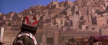 Movie still from “The Scorpion King” (2002), directed by Chuck Russell – A man wearing a crown standing in front of a city; Wide shot, Low angle