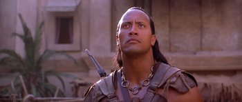 Movie still from “The Scorpion King” (2002), directed by Chuck Russell – A man with long black hair wearing a necklace; Close Up shot, Low angle