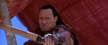 Movie still from “The Scorpion King” (2002), directed by Chuck Russell – A person holding a guitar; Close Up shot, High angle