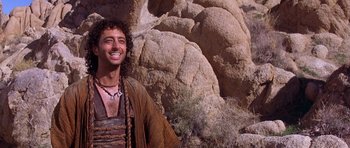 Movie still from “The Scorpion King” (2002), directed by Chuck Russell – A man smiling in front of a rock wall; Close Up shot, Low angle