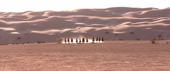 Movie still from “The Scorpion King” (2002), directed by Chuck Russell – A group of people riding horses through the desert; Extreme Wide shot, High angle