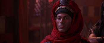 Movie still from “The Scorpion King” (2002), directed by Chuck Russell – A man wearing a red turban and a black hat; Close Up shot, Over the shoulder angle
