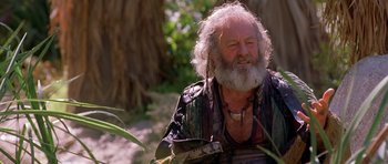 Movie still from “The Scorpion King” (2002), directed by Chuck Russell – An old man with a beard and a long white beard is sitting in the woods; Medium shot, Over the shoulder angle
