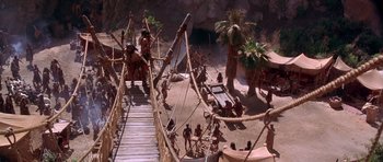 Movie still from “The Scorpion King” (2002), directed by Chuck Russell – A group of people sitting on top of a wooden bridge; Extreme Wide shot, High angle