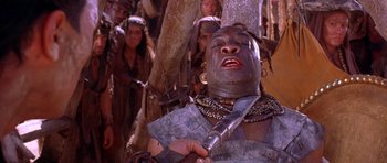 Movie still from “The Scorpion King” (2002), directed by Chuck Russell – A man with a knife in his hand and other people in the background; Close Up shot, Low angle