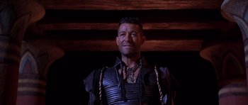 Movie still from “The Scorpion King” (2002), directed by Chuck Russell – A man in a leather outfit standing in front of a wooden wall; Medium shot, Low angle