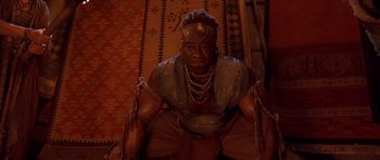 Movie still from “The Scorpion King” (2002), directed by Chuck Russell – A man in chains sitting on the ground; Medium shot, Low angle