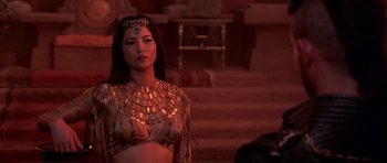 Movie still from “The Scorpion King” (2002), directed by Chuck Russell – A woman wearing a gold necklace and a red dress; Close Up shot, Over the shoulder angle