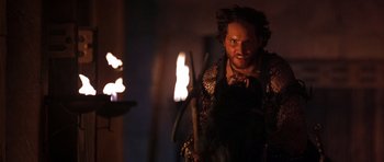 Movie still from “The Scorpion King” (2002), directed by Chuck Russell – A man holding a stick in front of a fire pit; Close Up shot, Over the shoulder angle