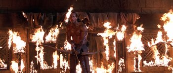 Movie still from “The Scorpion King” (2002), directed by Chuck Russell – A man that is holding a bow and arrow in front of fire; Medium shot, Low angle