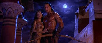 Movie still from “The Scorpion King” (2002), directed by Chuck Russell – A man and a woman standing next to each other in front of the moon; Medium shot, Low angle
