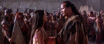 Movie still from “The Scorpion King” (2002), directed by Chuck Russell – A man and a woman are standing in front of a group of people; Medium shot, Over the shoulder angle