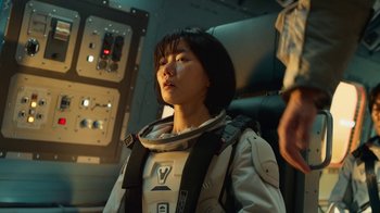 Movie still from “The Silent Sea” (2021), created by Choi Hang-Yong – A woman in a spacesuit sitting in a space ship; Medium shot, Over the shoulder angle