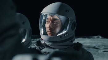 Movie still from “The Silent Sea” (2021), created by Choi Hang-Yong – A man in a space suit is looking at the camera; Close Up shot, Overhead angle