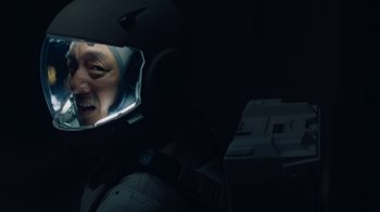 Movie still from “The Silent Sea” (2021), created by Choi Hang-Yong – A man wearing a helmet looking into a car mirror; Close Up shot, Overhead angle
