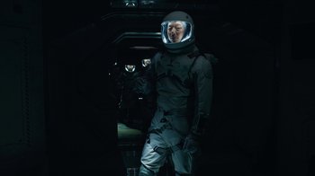 Movie still from “The Silent Sea” (2021), created by Choi Hang-Yong – A man in a spacesuit and helmet standing in a dark room; Medium shot, Overhead angle