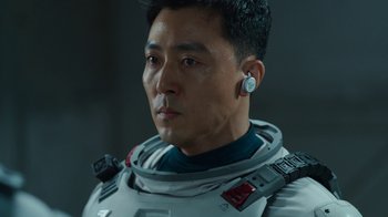 Movie still from “The Silent Sea” (2021), created by Choi Hang-Yong – A person wearing a suit and ear buds; Close Up shot, Low angle