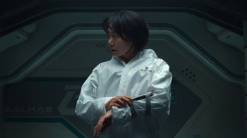 Movie still from “The Silent Sea” (2021), created by Choi Hang-Yong – A woman in a white jacket holding a pen; Medium shot, High angle
