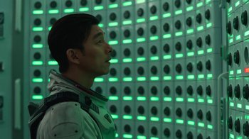 Movie still from “The Silent Sea” (2021), created by Choi Hang-Yong – A man standing in front of a wall of green lights; Medium shot, Low angle