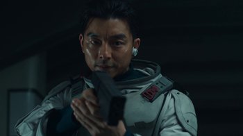 Movie still from “The Silent Sea” (2021), created by Choi Hang-Yong – A man in a space suit holding a gun; Close Up shot, Over the shoulder angle
