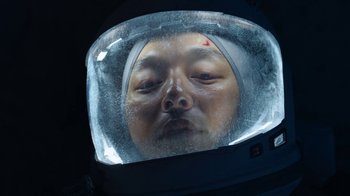 Movie still from “The Silent Sea” (2021), created by Choi Hang-Yong – A man wearing a space helmet looking into a mirror; Close Up shot, Overhead angle