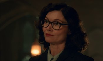 Movie still from “Guillermo del Toro's Cabinet of Curiosities” (2022), directed by Keith Thomas – A woman wearing a suit and glasses looking to her left; Close Up shot, Over the shoulder angle