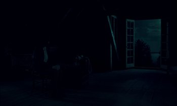 Movie still from “Guillermo del Toro's Cabinet of Curiosities” (2022), directed by Keith Thomas – A person sitting on a chair in a dark room; Extreme Wide shot, High angle