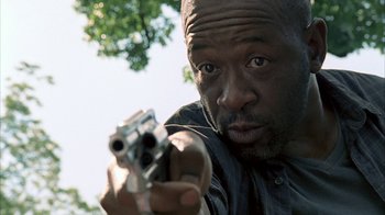 Movie still from “The Walking Dead” (2010), directed by Daniel Sackheim – A man holding a gun while wearing a black shirt; Close Up shot, Low angle