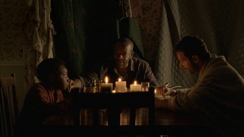 Movie still from “The Walking Dead” (2010), directed by Daniel Sackheim – A group of people sitting around a table with candles; Wide shot, High angle