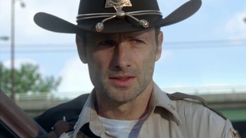 Movie still from “The Walking Dead” (2010), directed by Daniel Sackheim – A person wearing a hat; Close Up shot, Over the shoulder angle