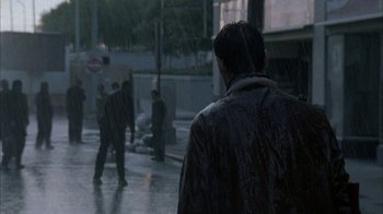 Movie still from “The Walking Dead” (2010), directed by Daniel Sackheim – A man is walking down the street in the pouring rain; Wide shot, Over the shoulder angle