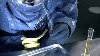 Movie still from “The Walking Dead” (2010), directed by Daniel Sackheim – A person in a blue suit is holding a yellow tube; Extreme Close Up shot, Overhead angle