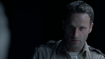 Movie still from “The Walking Dead” (2010), directed by Daniel Sackheim – A person wearing a shirt and jacket; Close Up shot, Over the shoulder angle