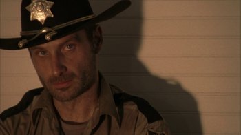 Movie still from “The Walking Dead” (2010), directed by Daniel Sackheim – A person wearing a hat; Close Up shot, Low angle