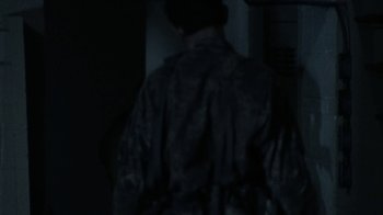 A person wearing a military uniform standing in a dark room