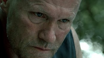 Movie still from “The Walking Dead” (2010), directed by Daniel Sackheim – An older man with a shaved head and blue eyes stares at the camera; Extreme Close Up shot, Low angle