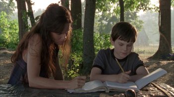 Movie still from “The Walking Dead” (2010), directed by Daniel Sackheim – A woman and a young boy writing on a book; Medium shot, High angle