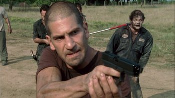 Movie still from “The Walking Dead” (2010), directed by Daniel Sackheim – A man holding a gun while standing in a field; Close Up shot, Over the shoulder angle